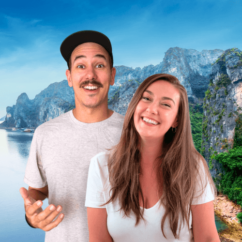 Smiling couple standing in front of a dramatic limestone cliff and turquoise water in Southeast Asia